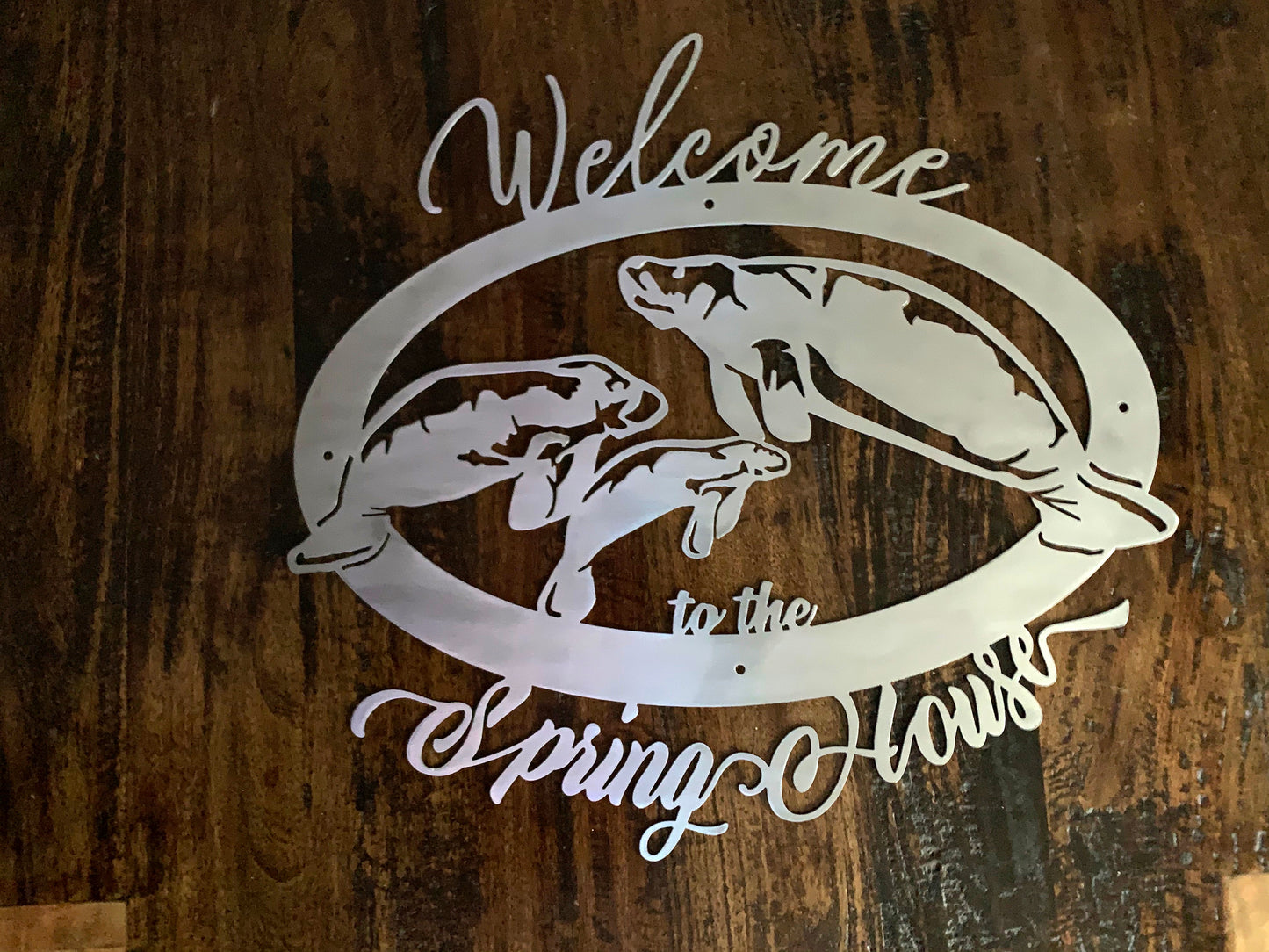 3 manatee sign in brushed metal over dark wood background alt view